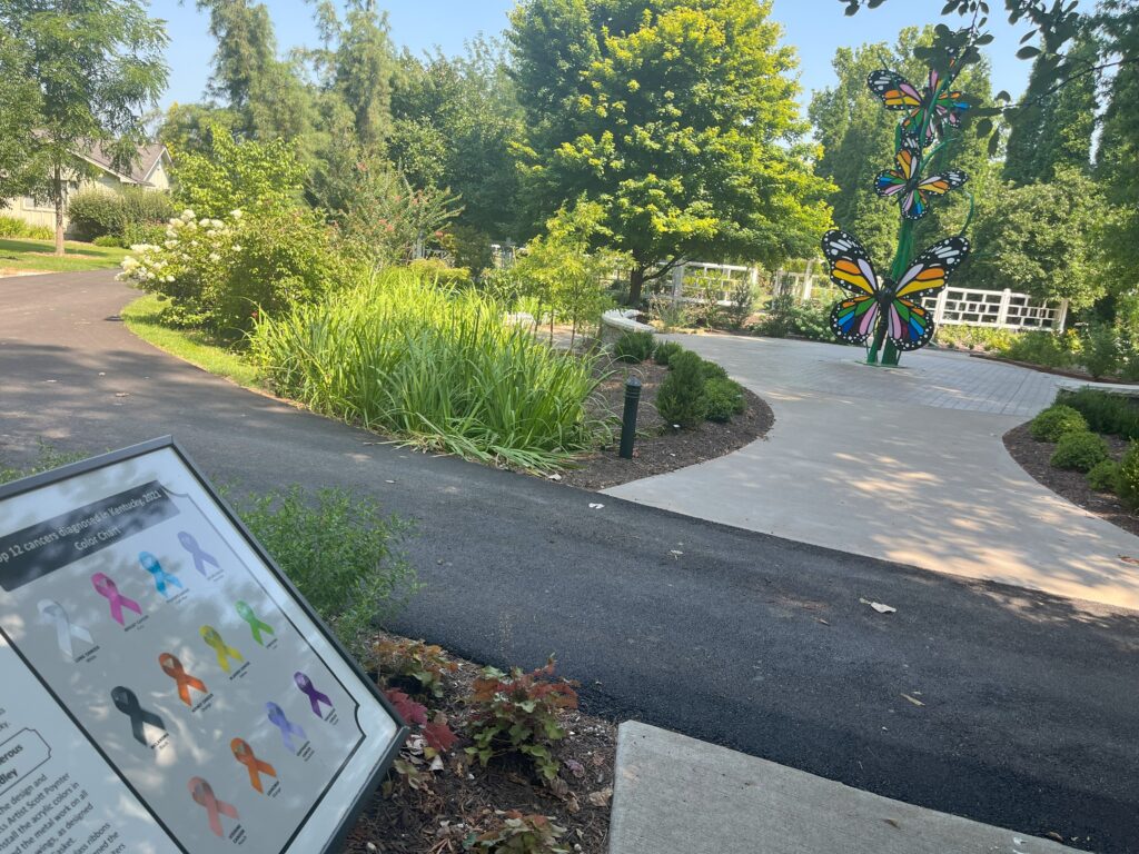 At the end of the Path of Hope and Healing is a color-coded chart listing the glass ribbons representing various cancers with a butterfly sculpture coming up.